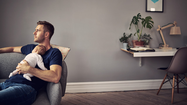 Man resting on sofa with kid resting on his chest